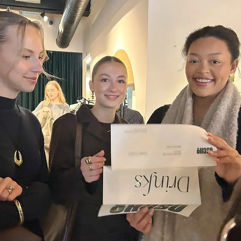 Drei Studentinnen halten einen Flyer und lesen gemeinsam.