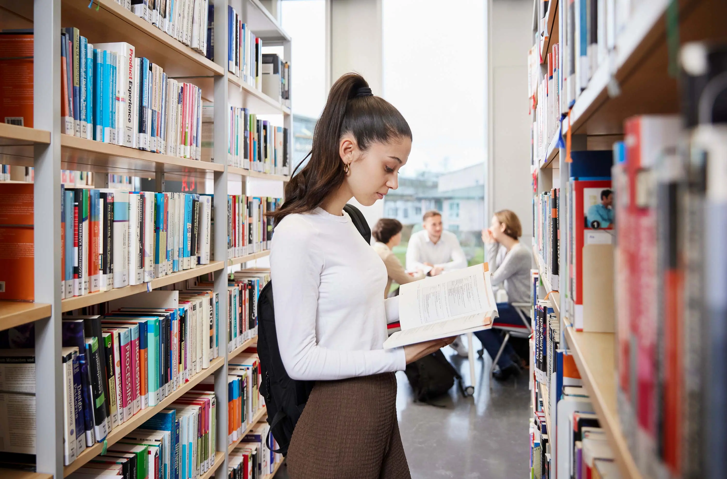Eine Studierende liest ein Buch in der Bibliothek der Hochschule der Medien.