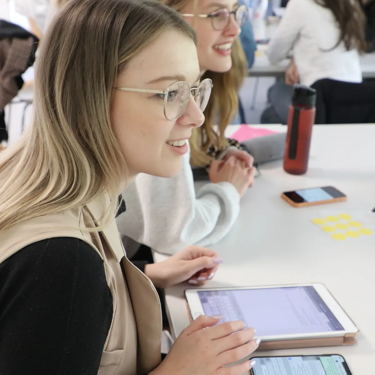 Eine Studentin sitzt am Tisch und hat vor sich ein Tablet liegen. 