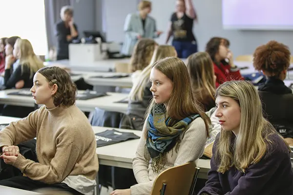 Neue Studierende sitzen im Hörsaal und lernen sich untereinander im Gespräch kennen.