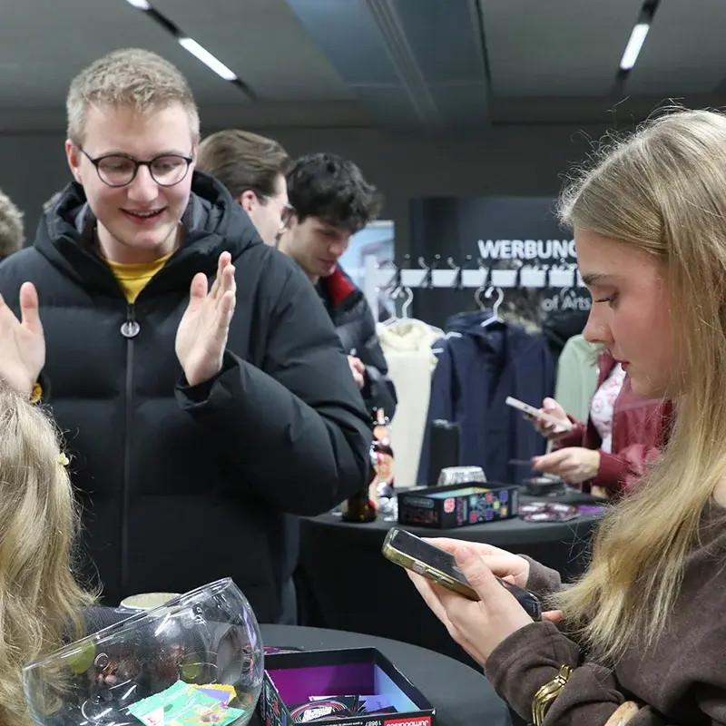 Studierende stehen am Stehtisch und spielen ein Spiel.